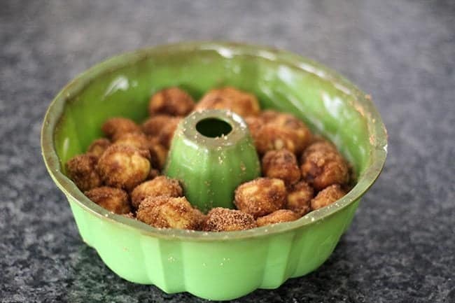 green bundt pan with ball shape doughs dipped in butter and sugar mixture