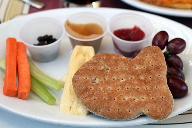 Peanut butter & jelly served with carrots, celery, and raisins in a white plate