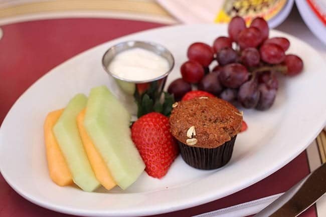 Bran muffin, yogurt and a pile of fruit in a white oval plate
