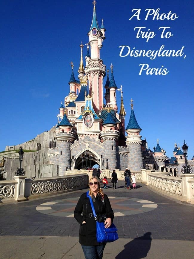 woman in black coat, wearing sun glasses in front of the castle at Disneyland Paris