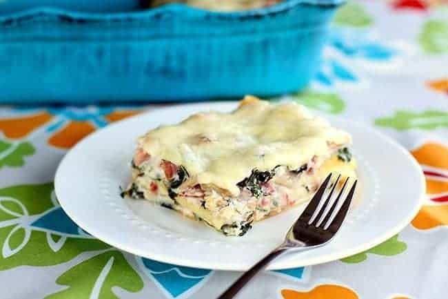 Cheesy Ham & Kale Lasagna serving in a white plate with fork