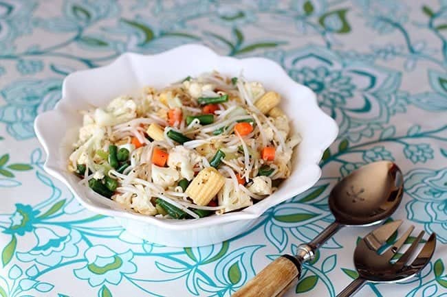 Marinated Vegetable Salad in a white ruffle bowl with spoon and fork beside it