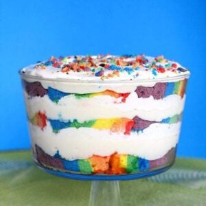 a cup of Rainbow Cake Trifle topped with whipped cream and left over rainbow cake crumbs