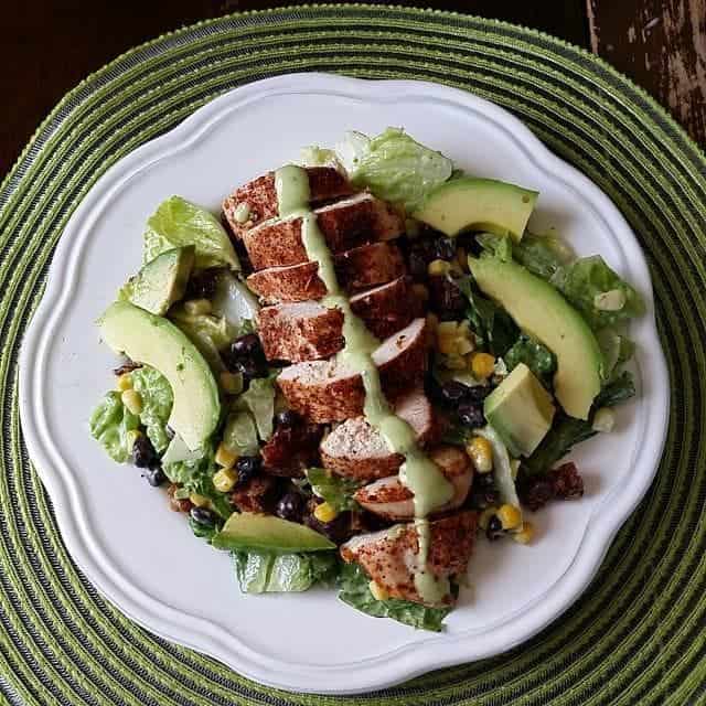 copycat Santa Fe Salad with avocado dressing on top in a white plate