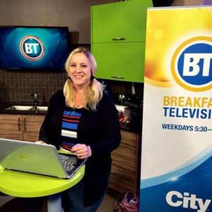 woman standing with her laptop on the table in Breakfast Television set up