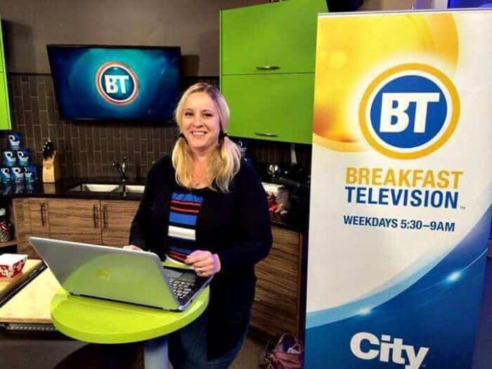 woman standing with her laptop on the table in Breakfast Television set up