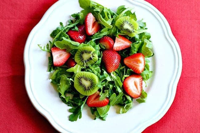 plain red tablecloth underneath a plate of Kiwi, Lime & Strawberry Salad