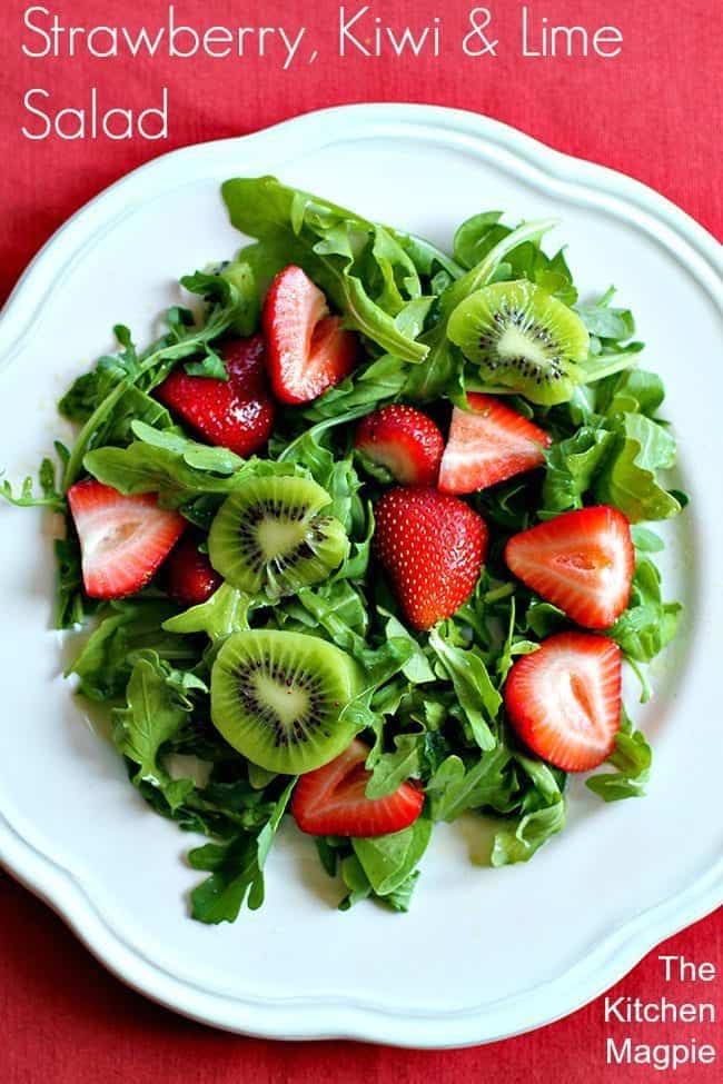 top down shot of a white plate with strawberry, kiwi and lime salad