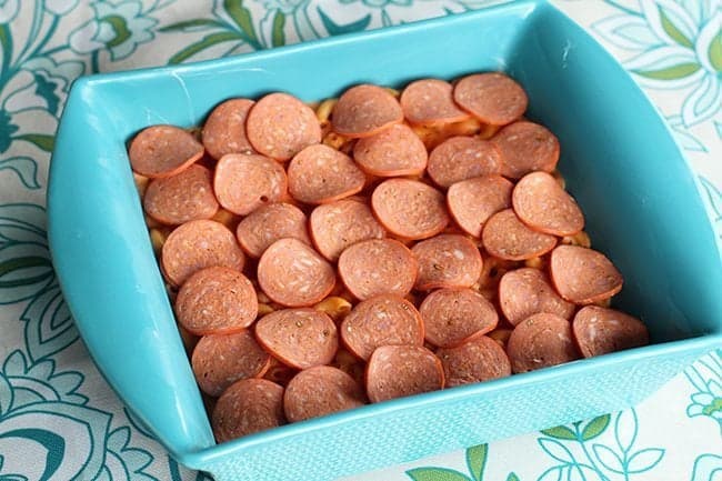 mac and cheese pizza sauce in a baking dish topped with pepperoni