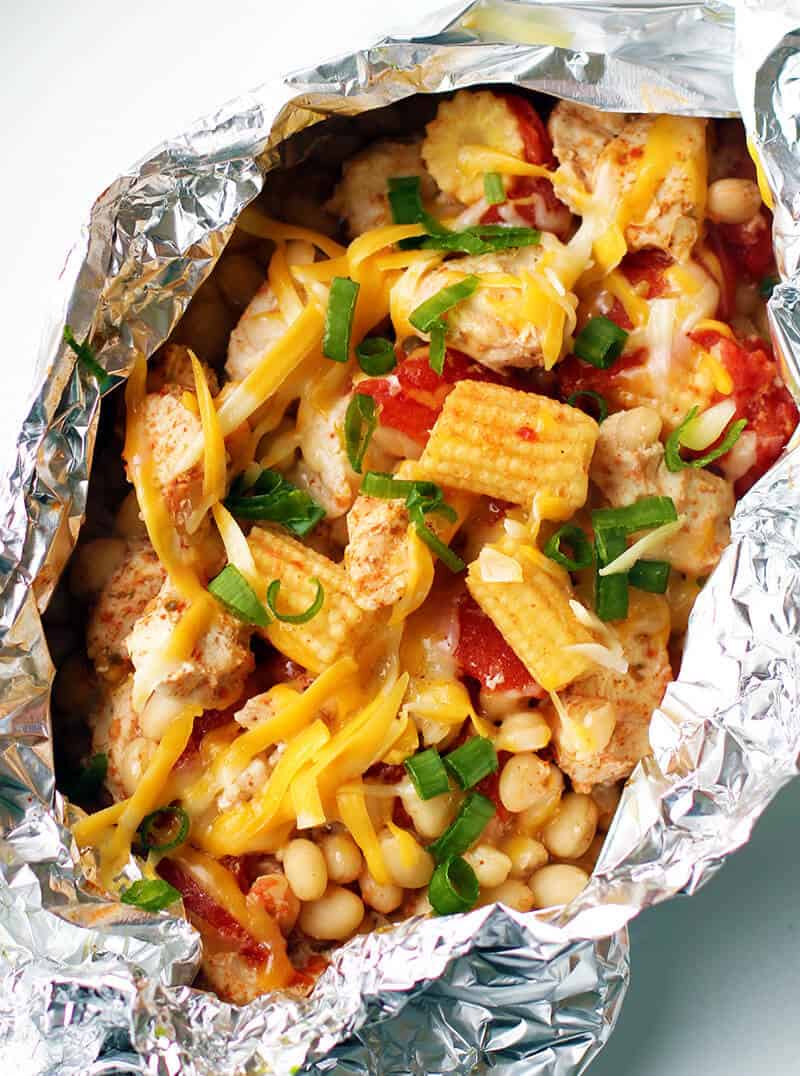 Close up of Chicken Foil Packets on a plate topped with cheese and green onions