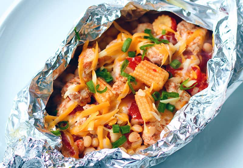 Campfire Tex Mex White Bean Chicken Foil Packets on a plate topped with cheese and green onions