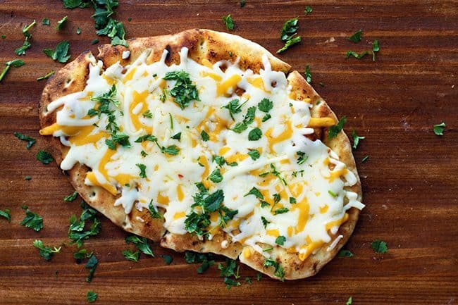 Tex Mex Cheesy Grilled Naan Bread sprinkled with chopped cilantro in a wood background