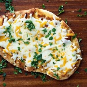 Top down shot of Tex Mex Cheesy Grilled Naan Bread sprinkled with chopped cilantro in a wood background