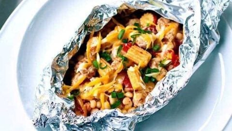 Close up of Chicken Foil Packets on a plate topped with cheese and green onions