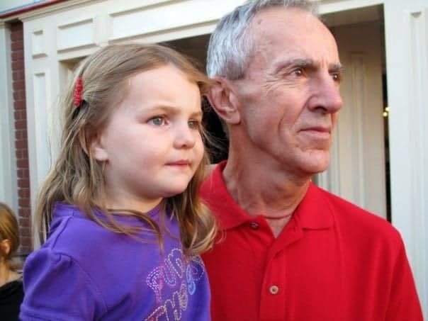 grandfather wearing red polo shirt and his granddaughter wearing violet shirt