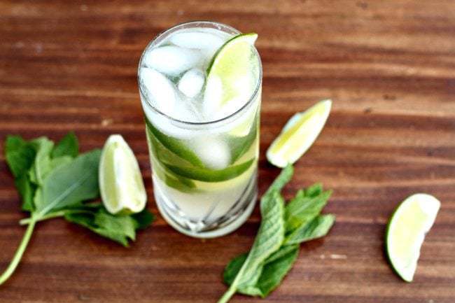 A glass of Mojito With Honey garnish with mint leaves and lime wedges