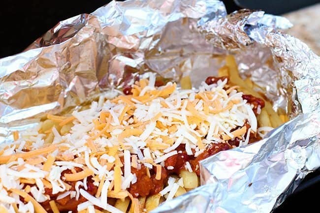 Campfire Chili Cheese Fries Tin Foil with can of chili on top and sprinkles of cheese