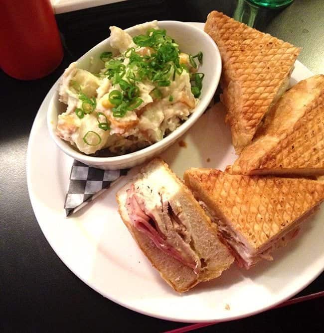 potato salad in a bowl topped with chopped green onions and monte cristo sandwich both in a white plate