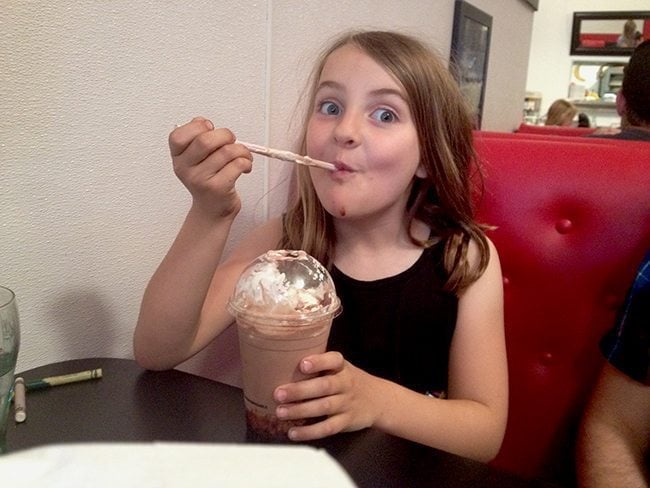 young girl sitting and holding her Milkshake