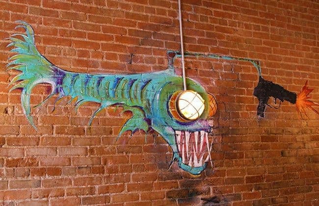 red brick wall with piranha like painting figure