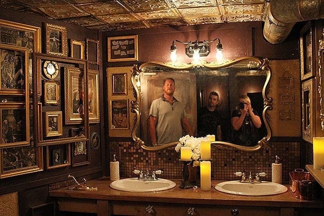 Women's washroom inside El Cortez with large mirror and vintage photo frames of different sizes