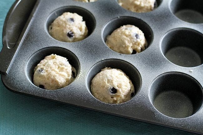 filling up the muffin tins with scoops of cookie dough