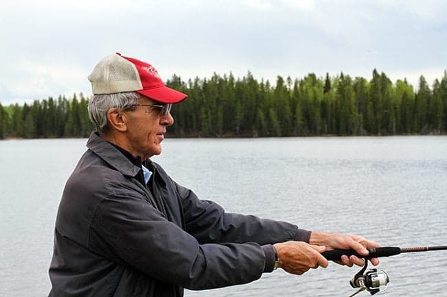 man wearing red white cap, holding fishing rod in the lake catching fish