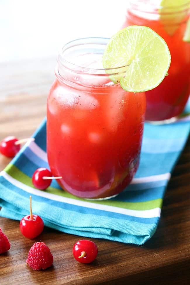 close up of Cherry & Raspberry Bourbon Lemonade on mason jars garnish with a slice of lemon