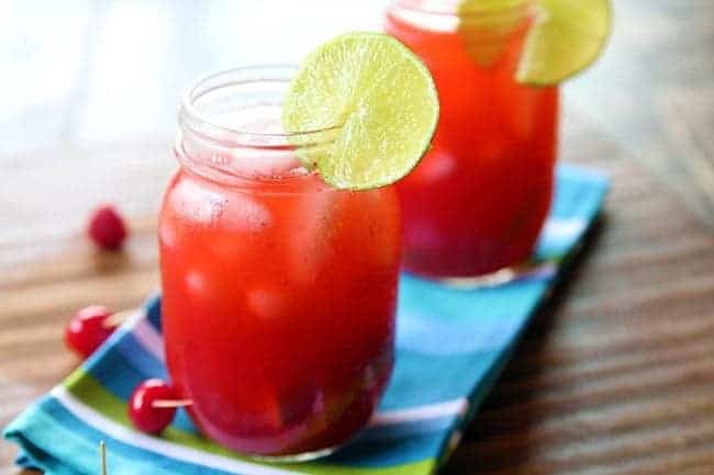 close up Cherry & Raspberry Bourbon Lemonade on mason jars garnish with a slice of lemon