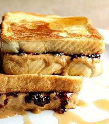 white plate with Peanut Butter & Jelly French Toast with syrup drizzled on top