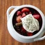 top down shot of chunky Ukrainian Borsch topped with sour cream and dill in a pot like white bowl