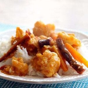 close up Curried Cauliflower and Carrots over rice in a white plate