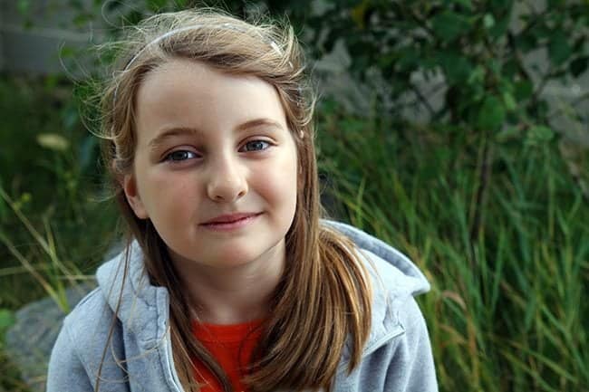 close up of a young girl on red shirt with ash grey jacket