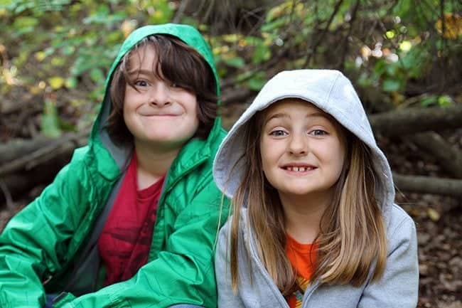 kids photo sitting in the outside with forest background