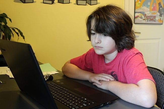 close up of a boy sitting, facing the laptop