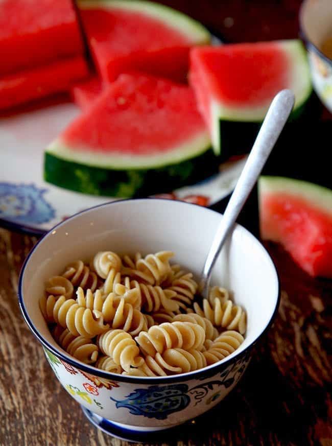 pasta in a bowl and sliced watermelons in a plate