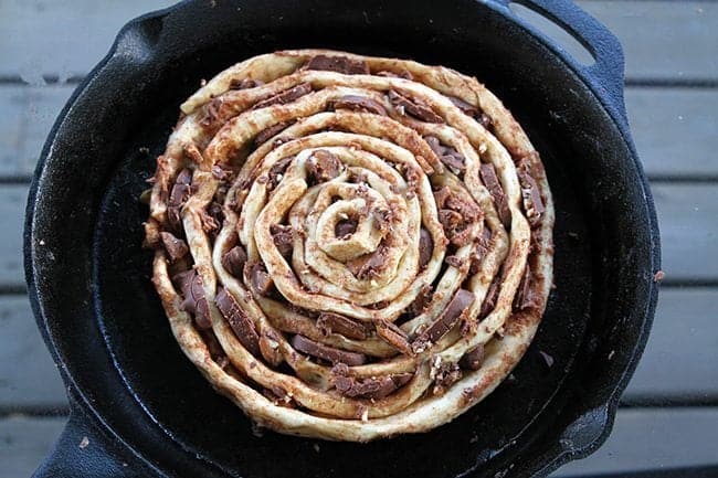5 cinnamon buns connected end to end and rolled up together in a skillet