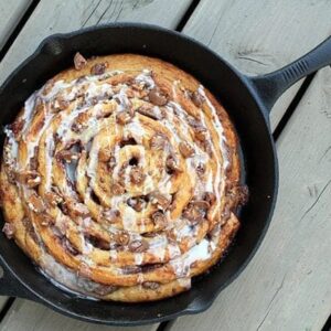 close up of Two Ingredient Giant Turtles Cinnamon Bun in a skillet on wood background