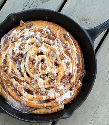 close up of Two Ingredient Giant Turtles Cinnamon Bun in a skillet on wood background