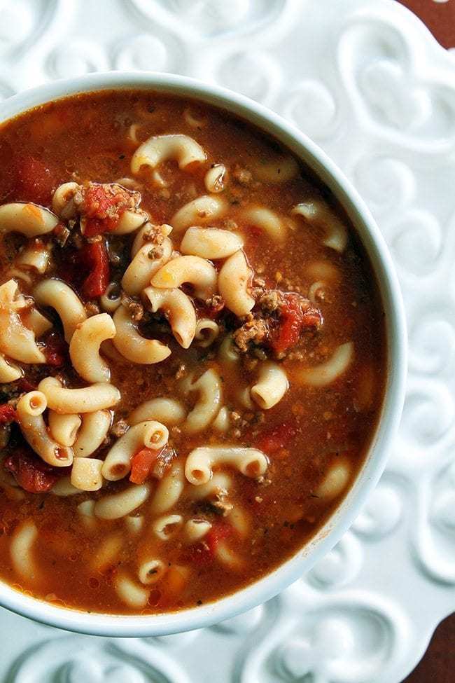close up of tomato beef macaroni soup in a white bowl