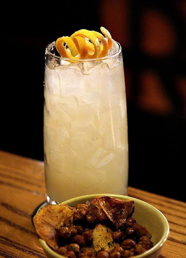 a glass of Paloma cocktail with lots of ice, garnished with peel of grapefruit