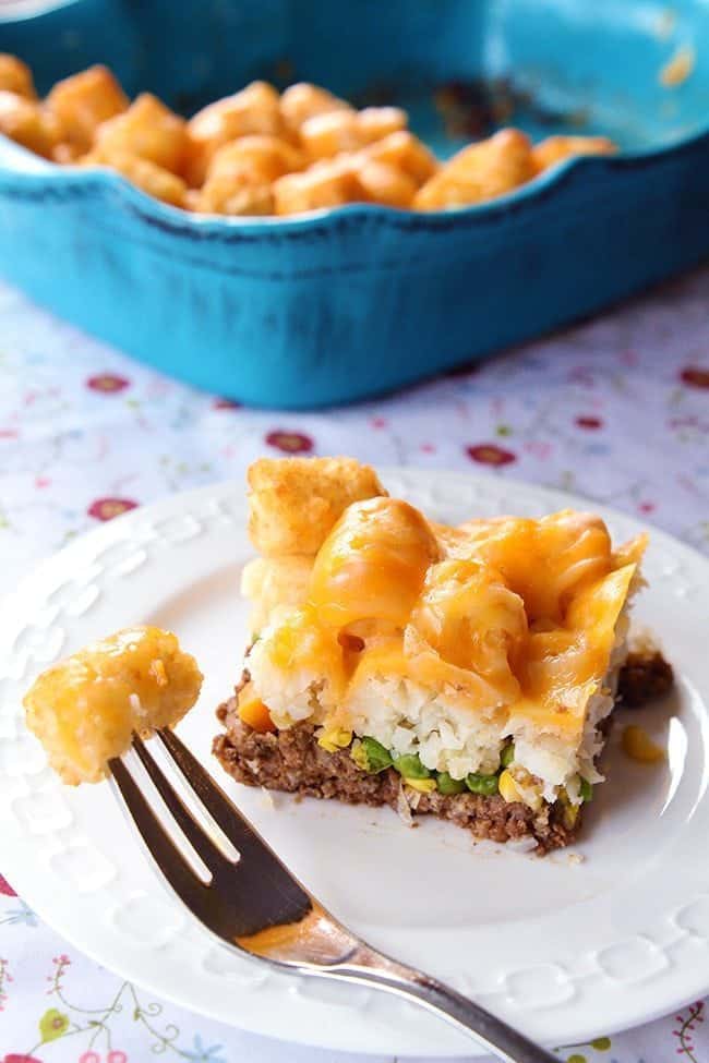 white plate with Tater Tots Shepherd's Pie, a blue casserole dish on background