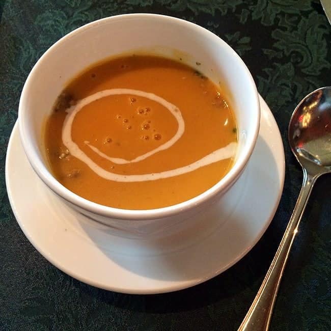 squash soup with toasted pumpkin seeds and fresh chives in a white bowl