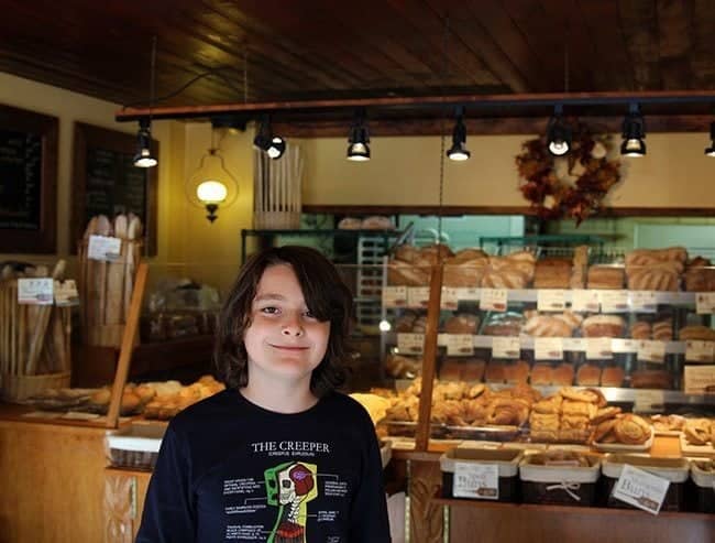 young boy's picture inside the bakery with lots of bread on his background