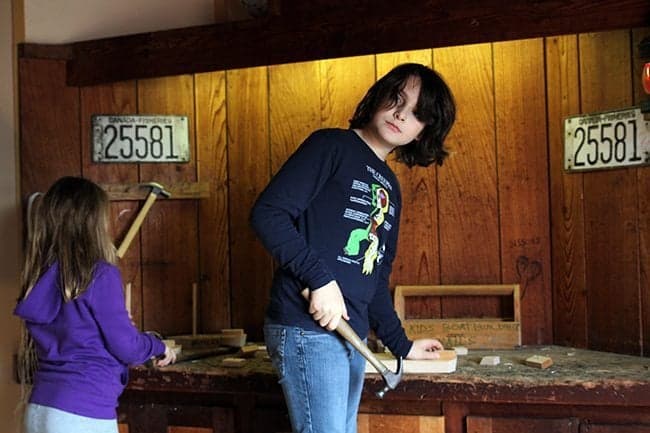 Two kids holding hammers and build their own wooden boats