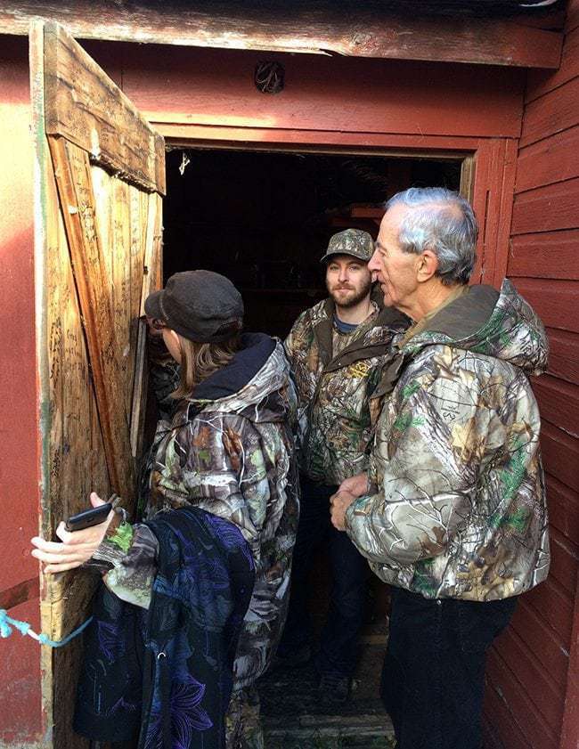 woman writing in a wooden door with two men behind her