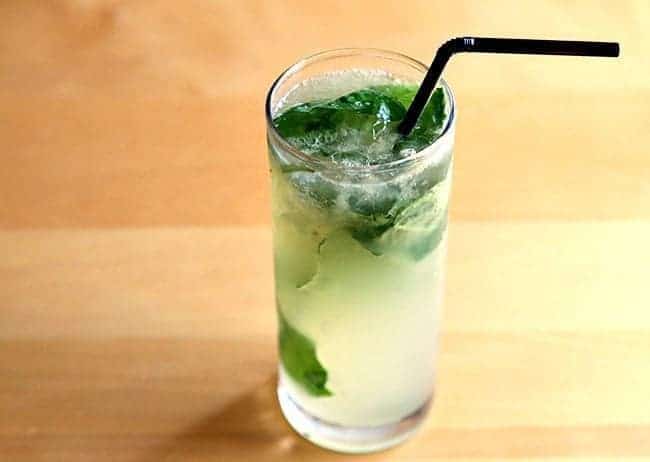 A glass of Gin Basil Smash with Black Straw