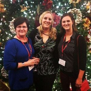 group picture of three ladies in front of tall Christmas tree