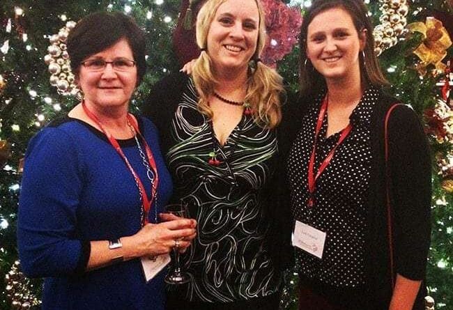 group picture of three ladies in front of tall Christmas tree