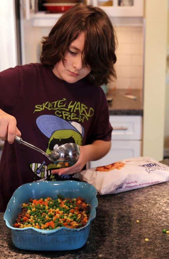 placing the various layers of toppings on a pan of cooked ground beef